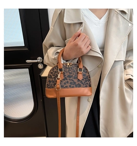 Close-up of leopard print shell bag with brown leather trim and golden hardware detailing