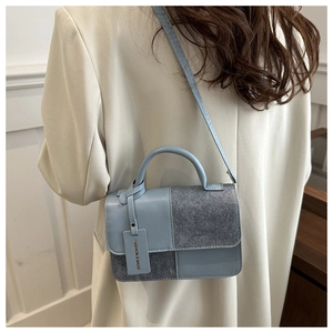 Detail of light blue and grey patchwork crossbody bag showing premium textured leather