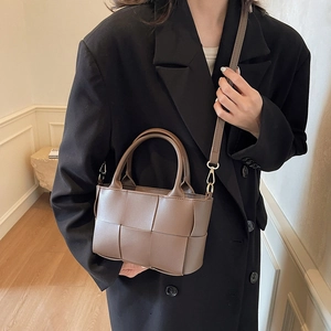Chic coffee brown woven bucket bag with top handle and strap shown on model in blazer