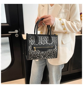 Detail of trendy leopard print tote bag with black handles and gold zipper accents