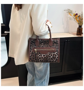 Leopard print tote bag with brown leather trim and metallic zipper detail shown on model