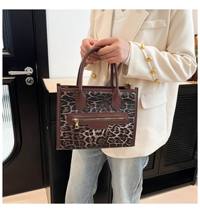 Detailed view of leopard print tote bag with brown handles and a stylish metal zipper