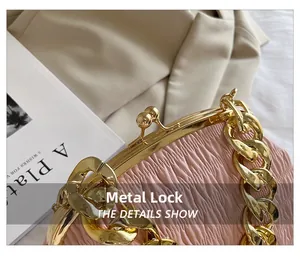 Close-up of ruched handbag with golden chain handle and vintage metal kiss-lock clasp