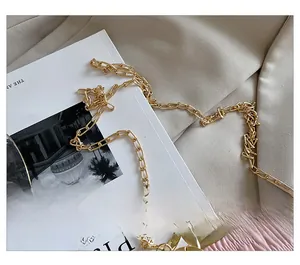 Detail of pink pleated cloud bag featuring a fine light gold chain strap and metal clasp