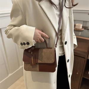 Sac bandoulière minimaliste en cuir et laine marron porté avec un long manteau beige
