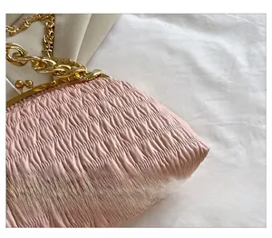 Detailed view of pink pleated shell bag with vintage kiss-lock and gold chain strap
