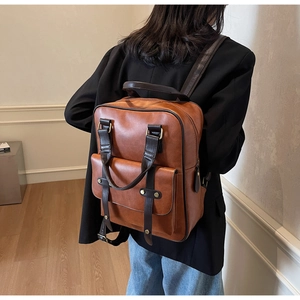 Bruine vintage kunstlederen rugzak met voorvak en gesp getoond op vrouwelijk model