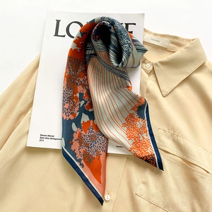 Artistic silk square scarf with floral pattern draped on shirt and magazine