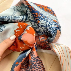 Detail of silk square scarf featuring orange and blue abstract landscape pattern textures