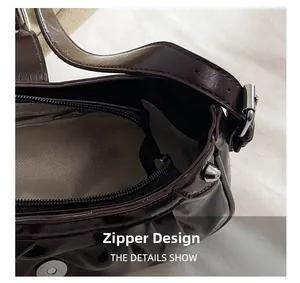 Detail of vintage brown shoulder bag showing zipper closure and grey herringbone lining