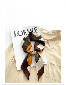 Detail of silk square scarf with geometric patchwork on a beige shirt collar