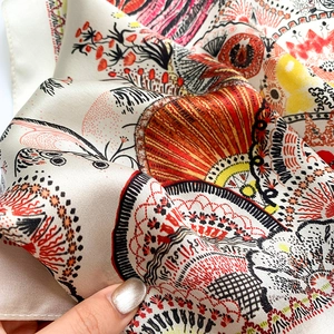 Macro detail of high-quality silk scarf showing artistic print and fine hand-rolled edges