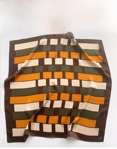 Macro detail of geometric pattern silk scarf with hand-rolled edges and smooth texture