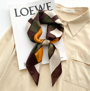 Detailed view of knotted silk scarf with plaid geometric patterns in warm earth tones