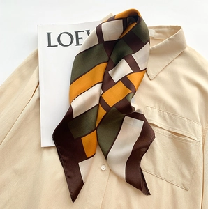 Detail of color-block silk scarf with geometric patterns on a beige shirt