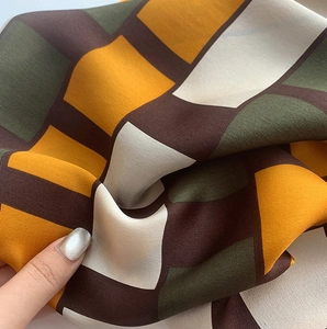 Detailed close-up showing the smooth silk texture and vintage geometric pattern of the scarf