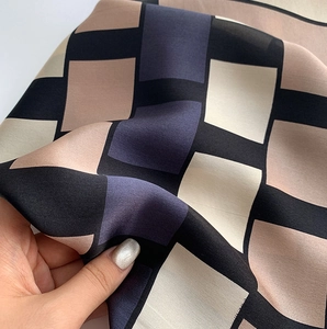 Detailed close-up showing the smooth texture and drape of a silk geometric scarf