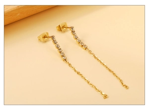 Détail de boucles d'oreilles pendantes dorées avec chaîne et strass blancs brillants