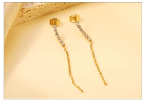 Détail de longues boucles d'oreilles en or avec pampilles et pierres en zircon blanc