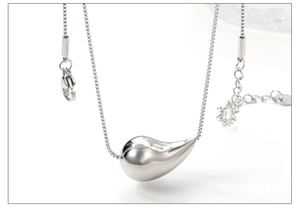 Macro detail of polished silver teardrop pendant on a stainless steel box chain necklace