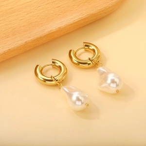 Elegant gold hoop earrings with baroque white pearl pendants on beige background