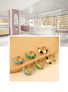 Detailed view of C-shaped bamboo earrings with colorful enamel sections in gold finish