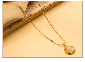 Nahaufnahme einer goldenen Perlenhalskette mit Vintage-Mondsteinanhänger auf Seide