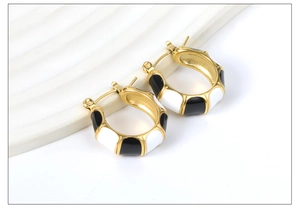 Detailed shot of C-shaped bamboo hoop earrings with gold, black and white enamel finish