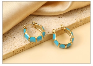 Detail of gold C-shaped bamboo texture earrings with light blue enamel inlay on stone