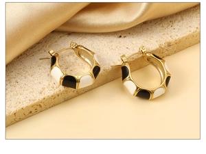 Detailed shot of black and white enamel C-shaped bamboo stud earrings on stone