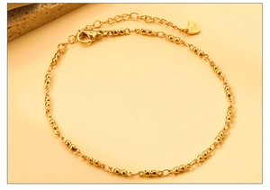 Détail de la chevillère dorée en acier inoxydable avec billes et pendentif cœur