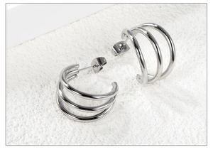 Macro view of silver triple-layered C-shaped earrings in polished stainless steel