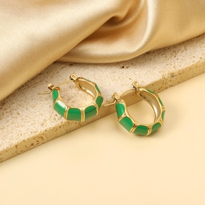 Gold-plated C-shaped bamboo earrings with green enamel on a luxury silk background