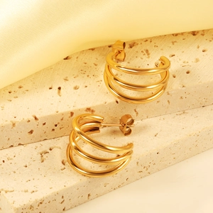 Elegant gold triple hoop earrings with a polished finish on a luxury silk background