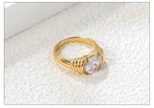 Macro shot of a gold oval ring with a large clear gemstone and textured band details