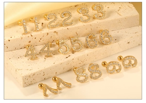 Close-up of gold-plated number earrings with white zircons and ball screw backs