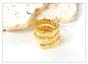 Macro view of 18K gold spiral layered ring with textured V-shape wheat pattern details
