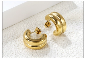 Macro shot of gold double-ribbed C-shaped earrings with polished metallic finish