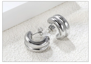 Macro shot of silver-toned double C-shaped hoop earrings with a high-polished mirror finish