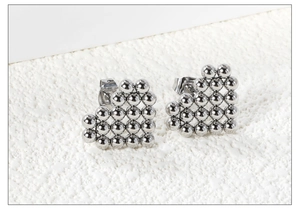 Detailed view of silver heart stud earrings crafted from polished steel beads