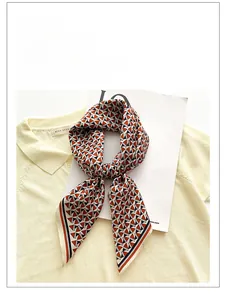 Detail of silk square scarf with geometric pattern draped on a yellow knit sweater