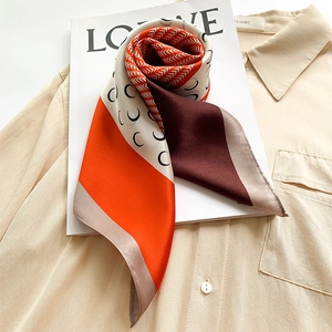 Detailed view of geometric silk scarf with orange and brown block patterns and fine edges