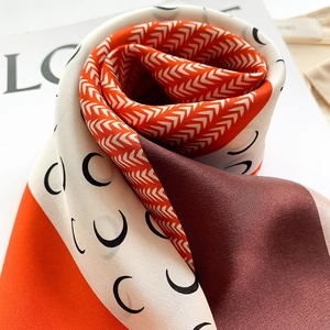 Detailed close-up of geometric pattern silk scarf with orange and black crescent prints