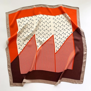Detail of silk scarf with crescent moon print and geometric zigzag patterns in orange and brown