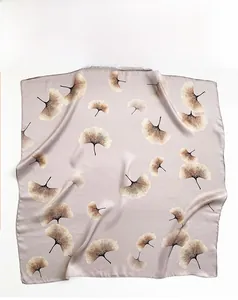 Detail of silk scarf with golden ginkgo leaf prints on a soft lotus pink background
