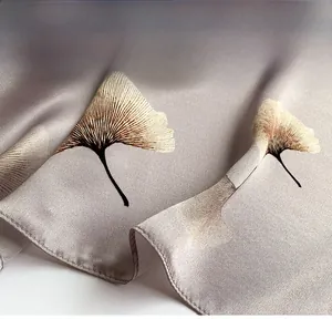 Detailed close-up showing fine stitching on silver silk scarf with ginkgo leaf pattern