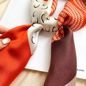 Detail shot of silk square scarf featuring orange and coffee geometric patchwork patterns