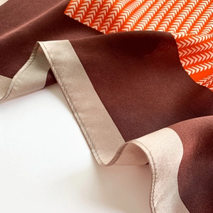 Close-up of silk square scarf showing detailed arrow pattern and fine rolled hem edges