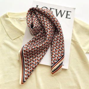 Silk-feel square scarf with orange and navy geometric patterns on a knit polo shirt