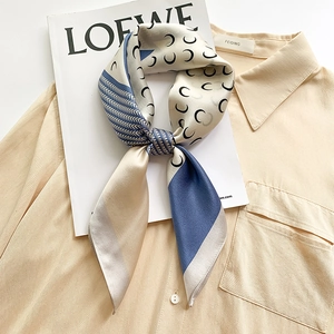 Elegant silk scarf with crescent moon patterns and geometric borders on a magazine
